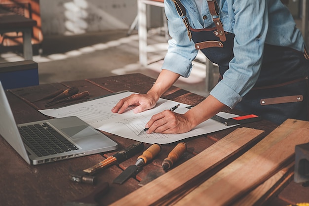 Charpentier travaillant avec des équipements sur une table en bois dans l'atelier de menuiserie.