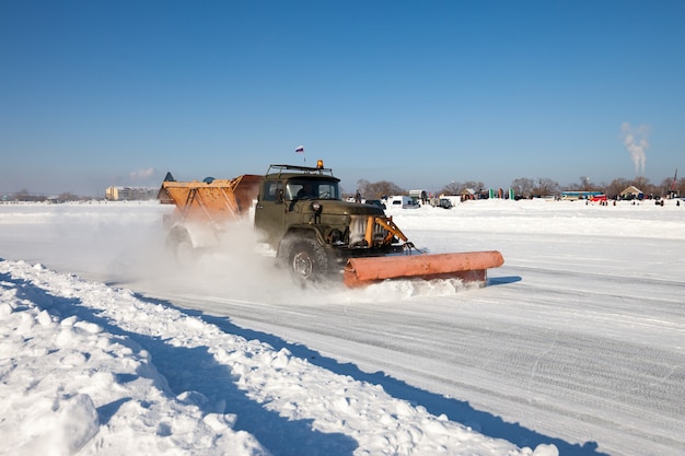 Le chasse-neige nettoie une route et la neige vole autour d'elle