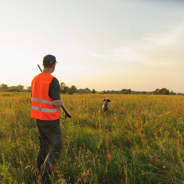 Chasseur à l'automne avec son chien de chasse au coucher du soleil.