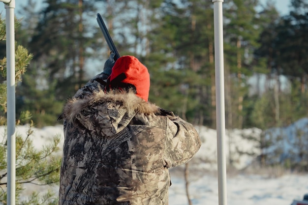 Chasseur en camouflage avec fusil dans la forêt d'hiver. Concept de chasse. Homme sécurisant une réserve, un jour de neige. Hunter vise d'une arme à feu dans la forêt enneigée