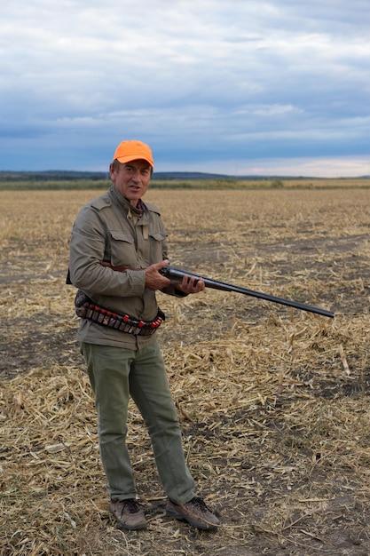 Chasseur de canard avec fusil de chasse marchant dans un pré