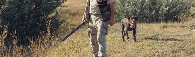 Chasseur de canard avec fusil de chasse marchant dans un pré