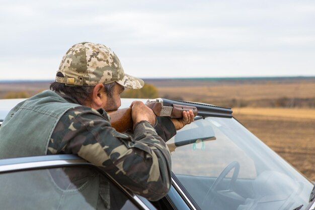 Chasseur de canard avec fusil de chasse marchant dans un pré