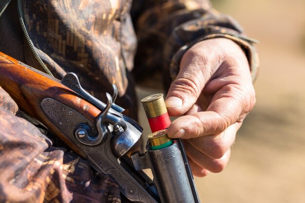 Chasseur de canard avec fusil de chasse marchant dans un pré.