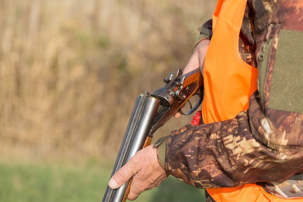 Chasseur de canard avec fusil de chasse marchant dans un pré.