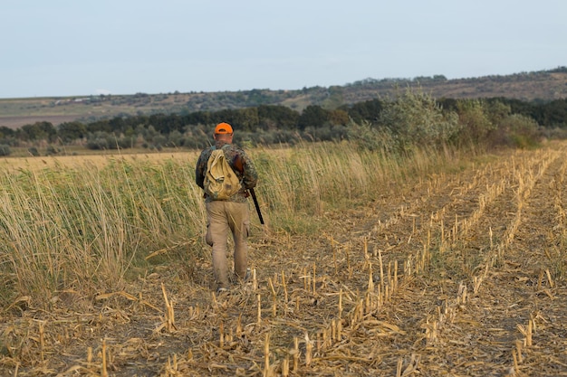 Photo chasseur de faisan avec fusil de chasse marchant dans un pré