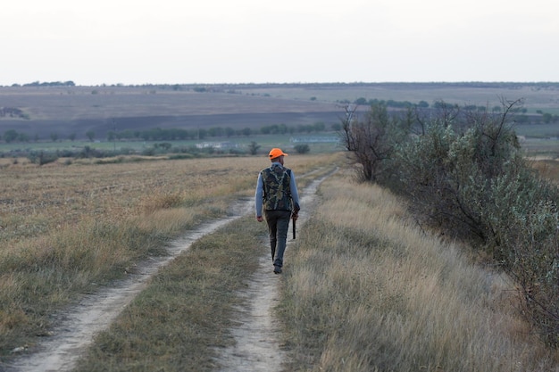 Chasseur de faisan avec fusil de chasse marchant dans un pré