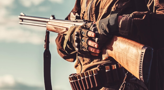 Un chasseur avec un fusil de chasse et un formulaire de chasse pour chasser dans une forêt d'automne. L'homme est en chasse. Homme chasseur. Période de chasse, saison d'automne. Homme avec une arme à feu.