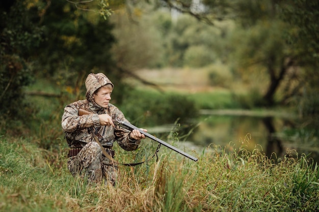 Chasseur d'homme avec fusil de chasse en forêt