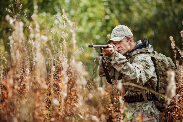 Chasseur d'homme avec fusil de chasse en forêt