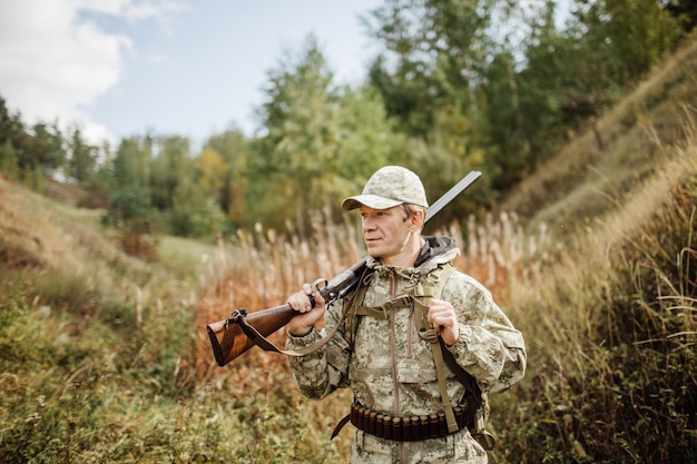 Chasseur d'homme avec fusil de chasse en forêt