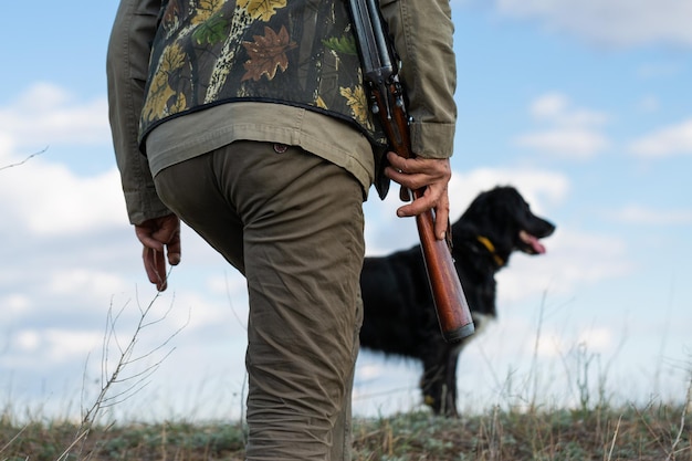 Photo chasseur d'homme mûr avec arme à feu tout en marchant sur le terrain avec vos chiens