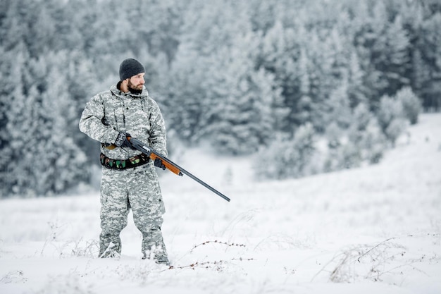 Chasseur mâle en tenue de camouflage à la recherche de sa cible ou de sa proie Scène d'hiver