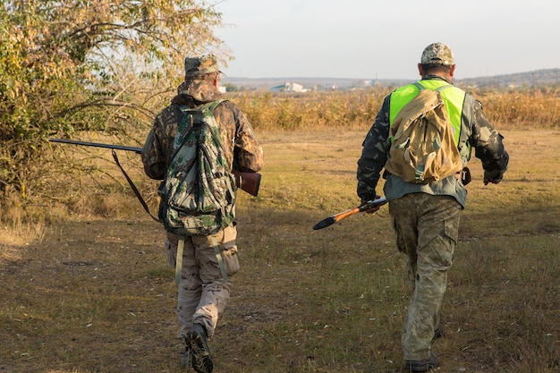 Chasseur en tenue de camouflage avec une arme à feu pendant la chasse à la recherche d'oiseaux sauvages ou de gibier Saison de chasse d'automne