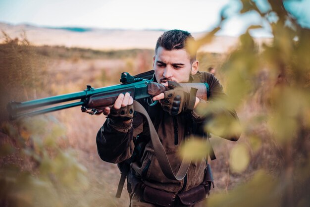 Chasseur visant un fusil dans la forêt chasseur avec un fusil de chasse sur la piste de chasse vers le bas