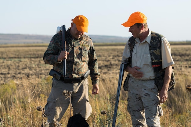 Chasseurs de canard avec fusil de chasse marchant dans un pré