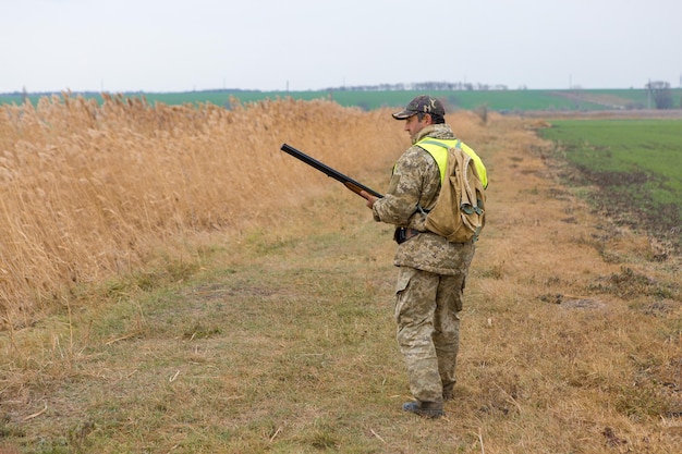 Chasseurs de faisan avec fusil de chasse marchant dans un pré.