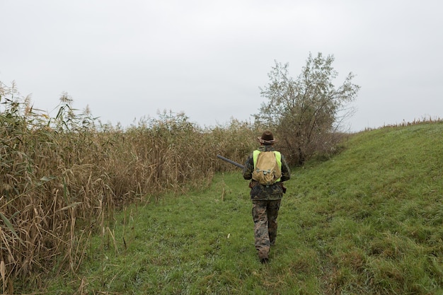 Chasseurs de faisans avec fusil de chasse marchant dans un pré.