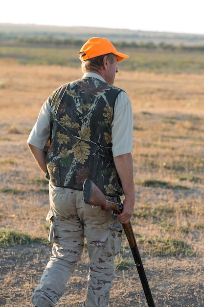 Chasseurs de faisans avec fusil de chasse marchant dans un pré.