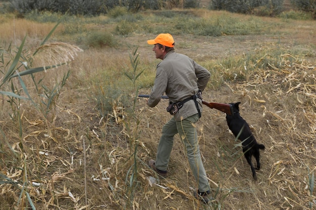 Chasseurs de faisans avec fusil de chasse marchant dans un pré.