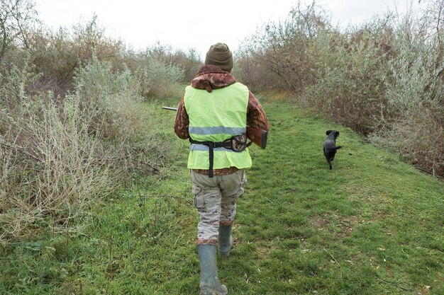 Chasseurs de faisans avec fusil de chasse marchant dans un pré.