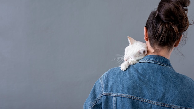 Chat blanc assis sur une épaule femelle