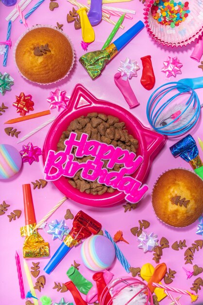 Chat de compagnie joyeux anniversaire fond avec ensemble différents chats et kitty collations et jouets chat museau forme bol anniversaire cupcakes avec joyeux anniversaire bougies accessoires Flatlay sur fond rose