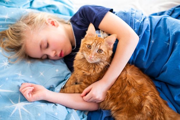 Chat Moelleux Au Gingembre Avec Une Petite Fille Endormie Sur Le Lit Bleu