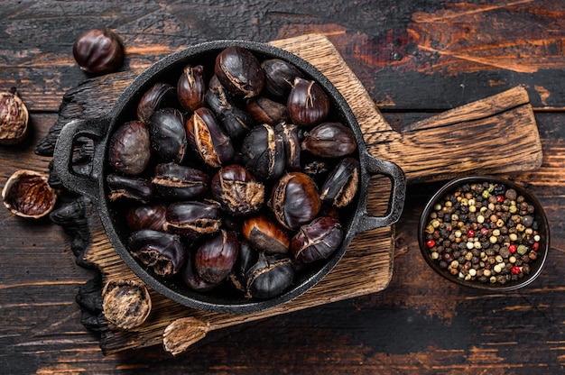 Châtaignes grillées servies dans une casserole sur une planche à découper en bois.