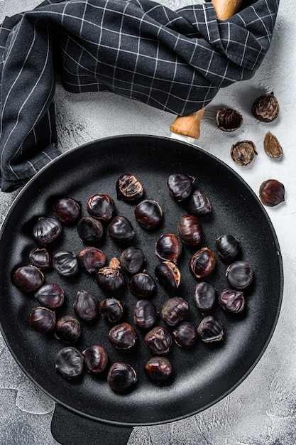 Châtaignes rôties dans une casserole sur une table en bois. Vue de dessus.