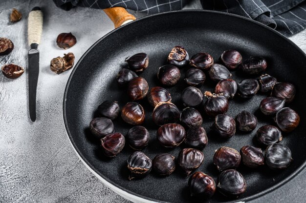 Châtaignes rôties dans une casserole sur une table en bois. Vue de dessus.