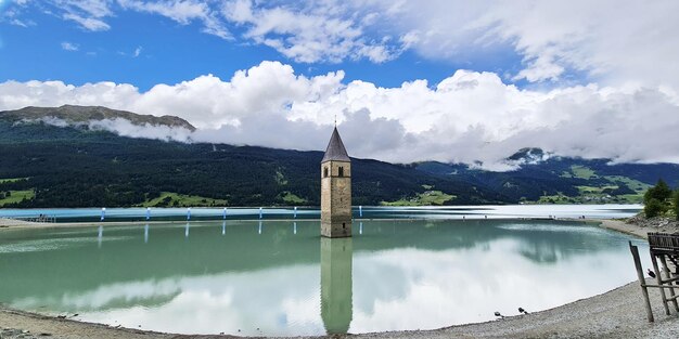 Un château d'eau au milieu d'un lac avec des montagnes en arrière-plan.