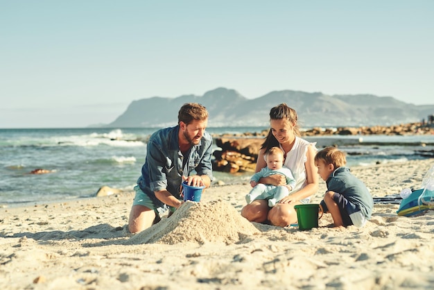 Château de sable construisant des parents et des enfants à la plage avec amour et soutien