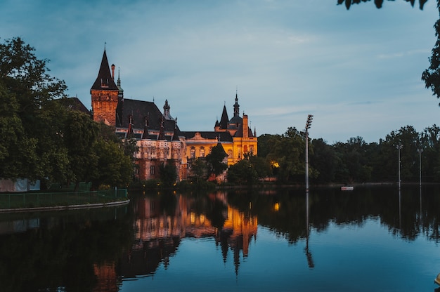 Château Vajdahunyad à Budapest au coucher du soleil avec la réflexion de l'eau.