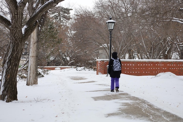 Photo chaudement habillée pour le mauvais temps canadien, une fille en pantalon de ski sur le fond d'un parc d'hiver.