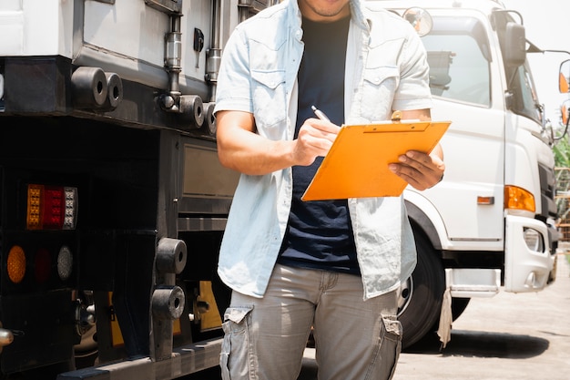 Un chauffeur de camion tenant le presse-papiers vérifiant la sécurité de la liste de contrôle d'un camion