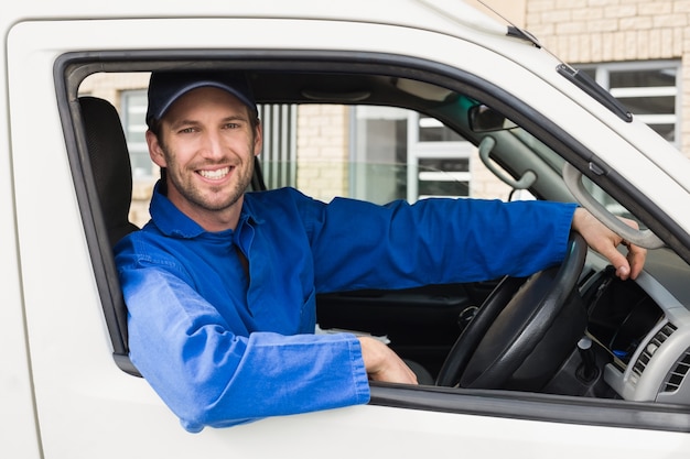 Chauffeur-livreur souriant à la caméra dans sa camionnette