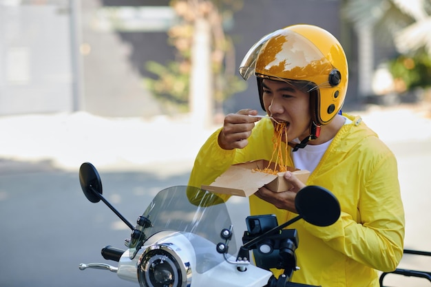 Un chauffeur de taxi sur moto qui déjeune.