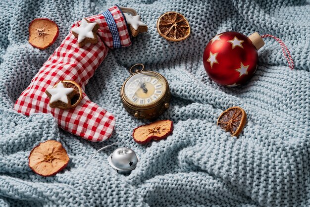 Chaussette de Noël remplie de biscuits étoilés et décorée d'oranges sèches, d'une horloge et d'un jouet de Noël sur un plaid bleu. Concept de Noël confortable