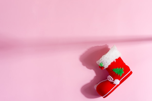 Chaussette de Noël rouge à décor festif sur un rose pastel. Vue de dessus.