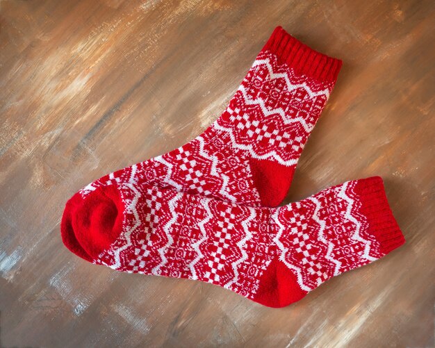 Photo chaussettes chaudes de noël avec des ornements rouges et blancs sur fond de bois marron se bouchent