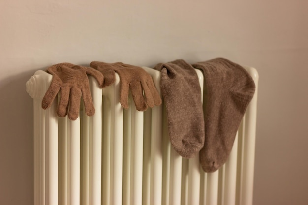 Photo chaussettes et gants sur le radiateur dans le concept de chambre de chauffage domestique conservation de la chaleur et économies de séchage des vêtements