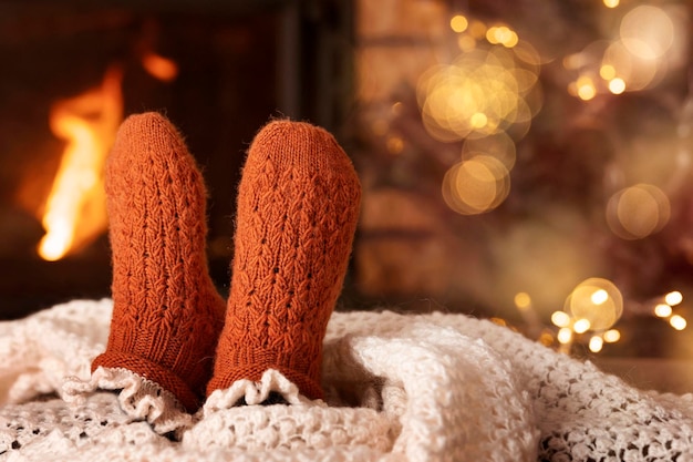 Chaussettes par Fireplace. Pieds dans des chaussettes tricotées en laine chaudes au coin du feu. Maison de soirée de Noël confortable