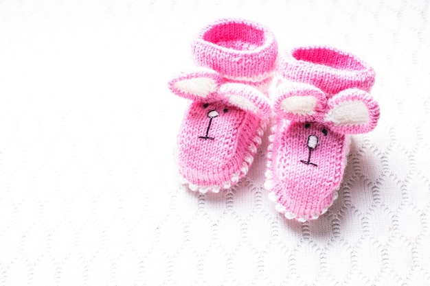 Chaussons bébé rose tricoté avec museau de lapin sur fond textile