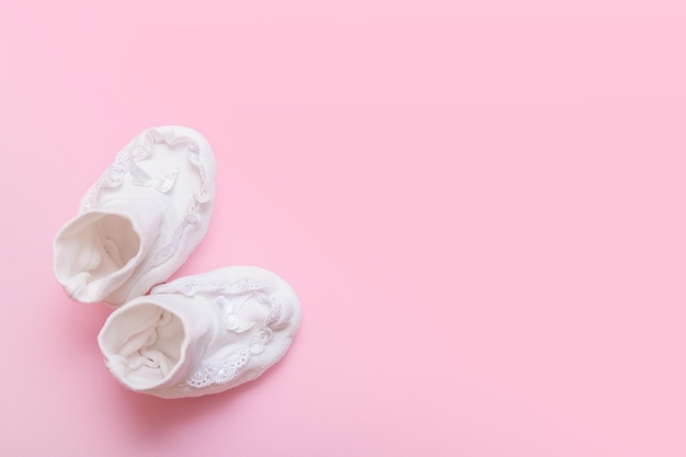 Chaussons blancs pour nouveau-né sur fond rose avec espace de copie