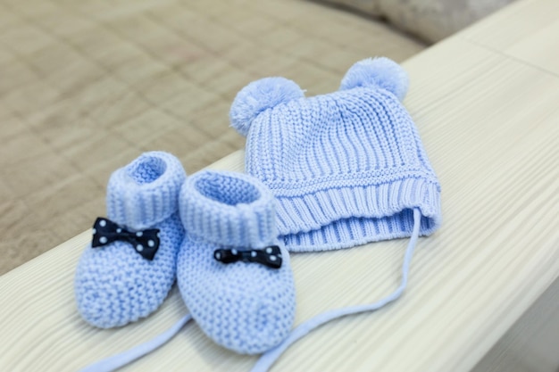 Des chaussons bleus et un chapeau sont posés sur une table.