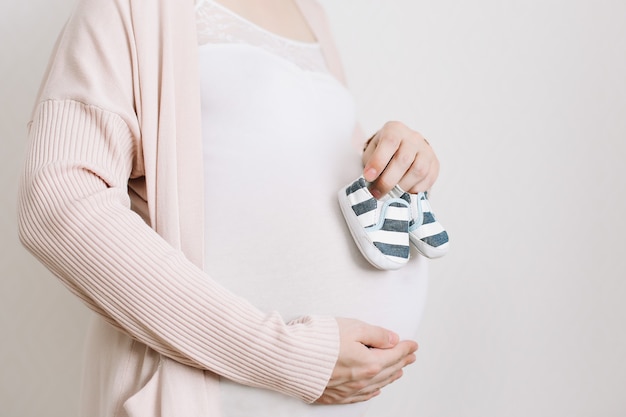 Chaussons entre les mains d'une future mère au ventre de femme enceinte