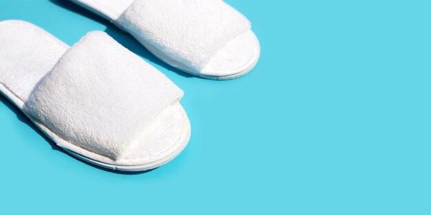 Chaussons d'hôtel sur fond bleu Copier l'espace