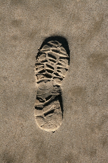 Photo chaussure empreinte sur une texture de sable brun sur la plage