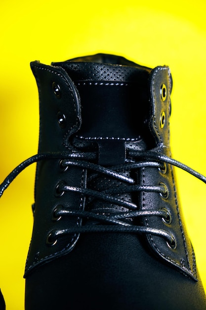 Chaussure homme noire à lacets sur fond jaune.